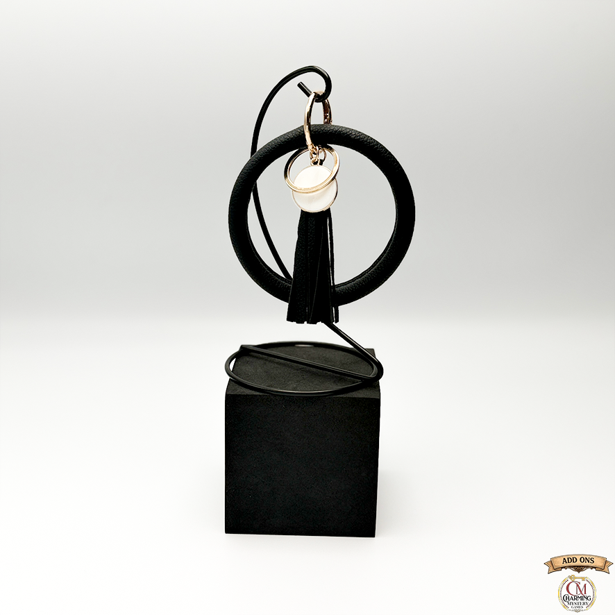 Black circular keychain with tassel on a white background