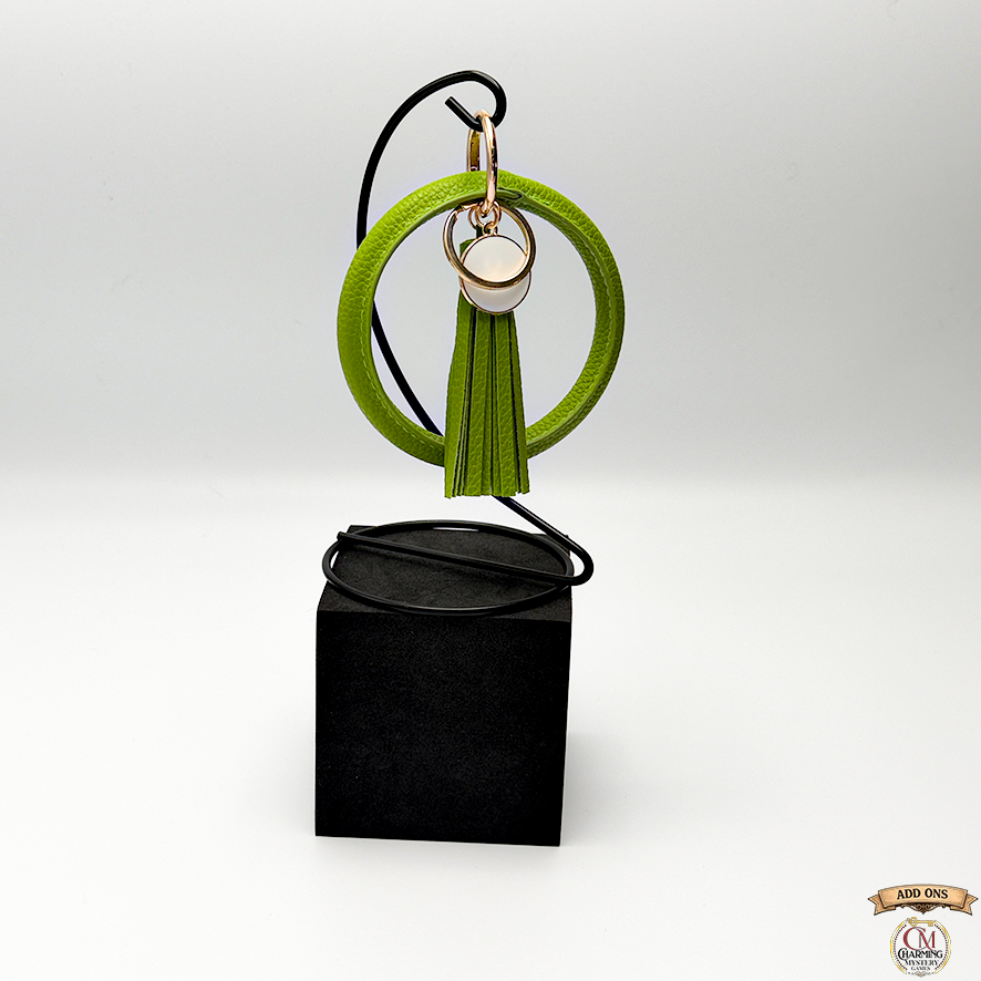 Green tassel keychain on a black stand with a white background