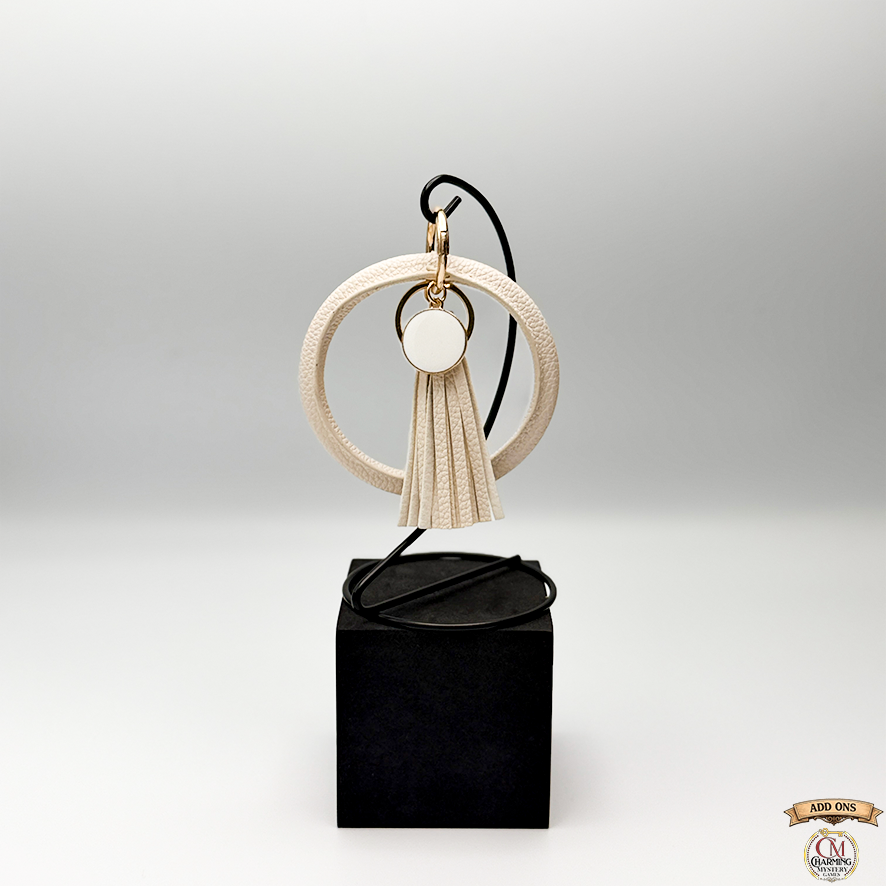 Decorative keychain with tassel on a black box against a light gray background