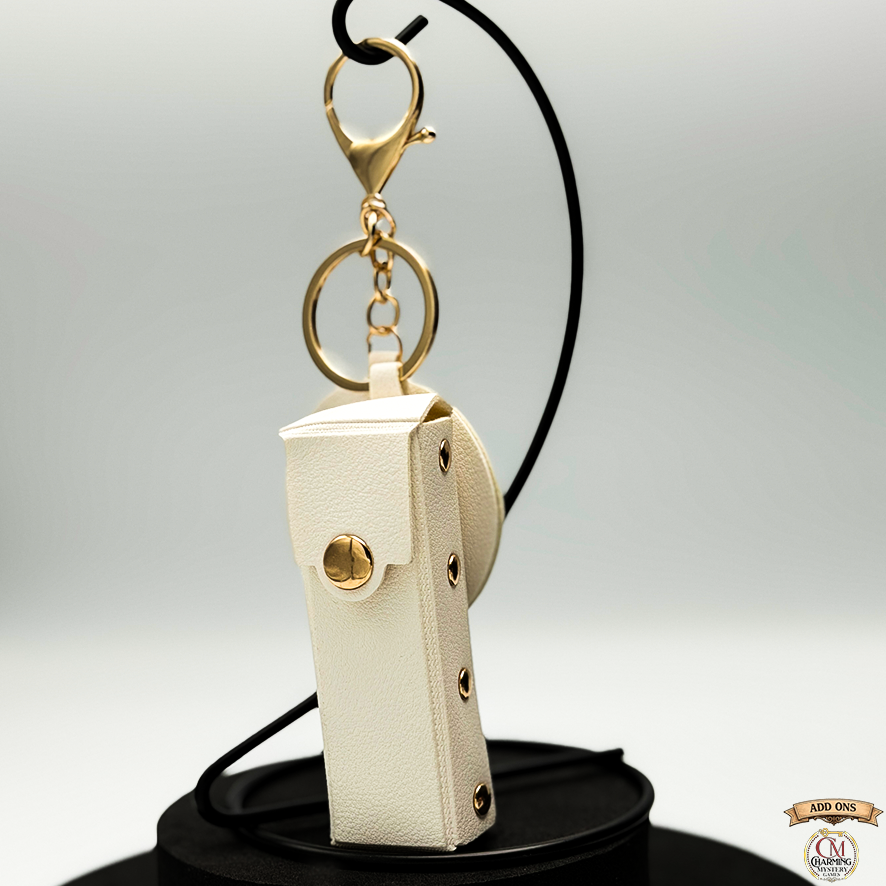 Beige leather keychain with gold accents on a gray background