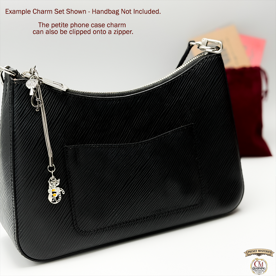 Black handbag with a charm on a white background.