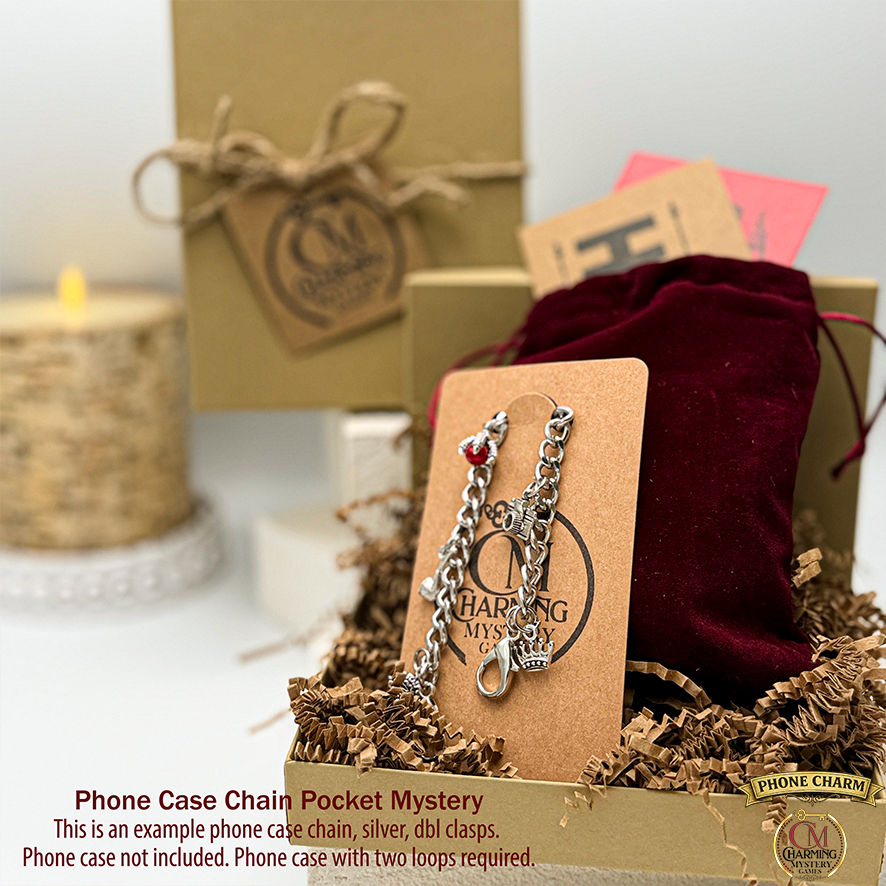 A cute silver phone case charm chain is on a card in front of a velveteen pouch with two envelopes. In the background is a mysterious kraft jewelry box.