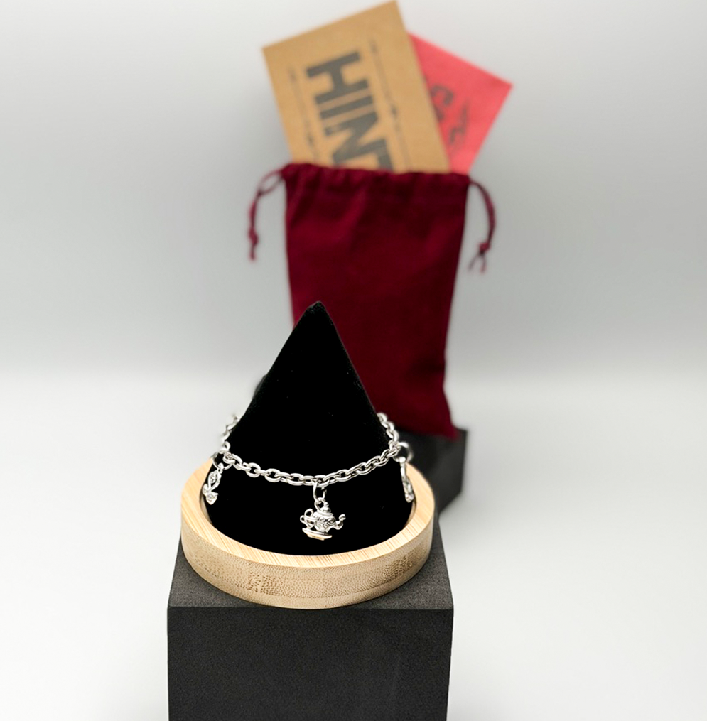Silver bracelet on a black stand with a red drawstring bag in the background