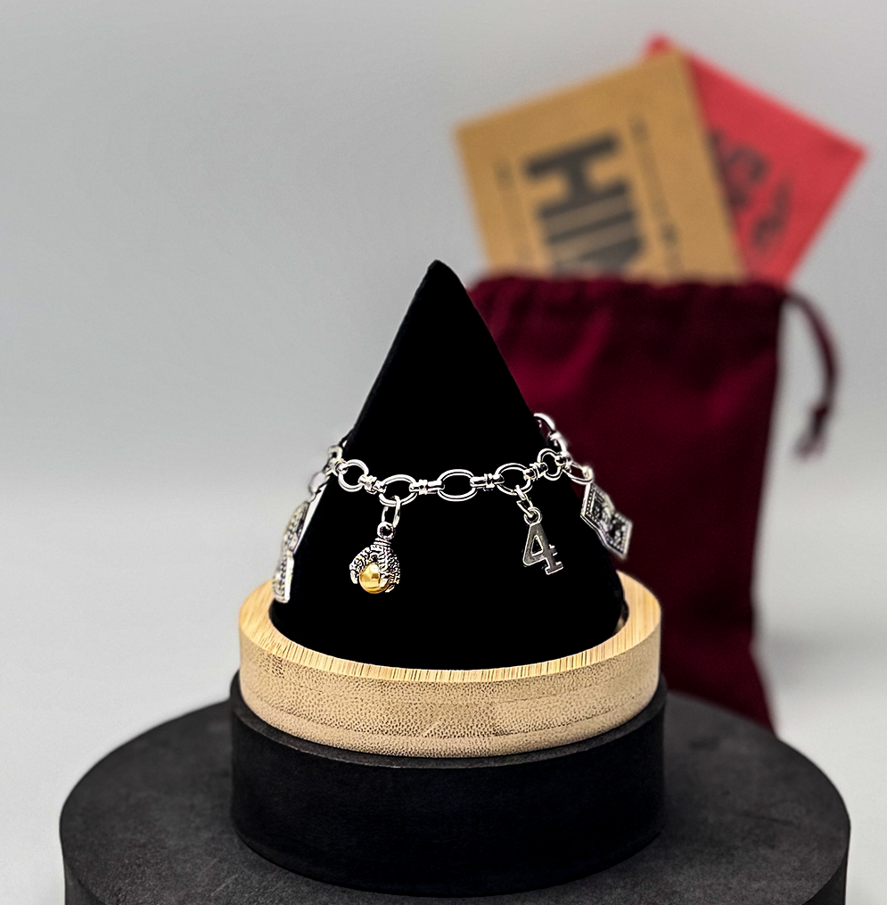 Silver bracelet with charms on a black and beige stand against a neutral background