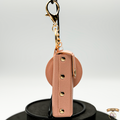 Pink leather keychain with gold accents on a white background