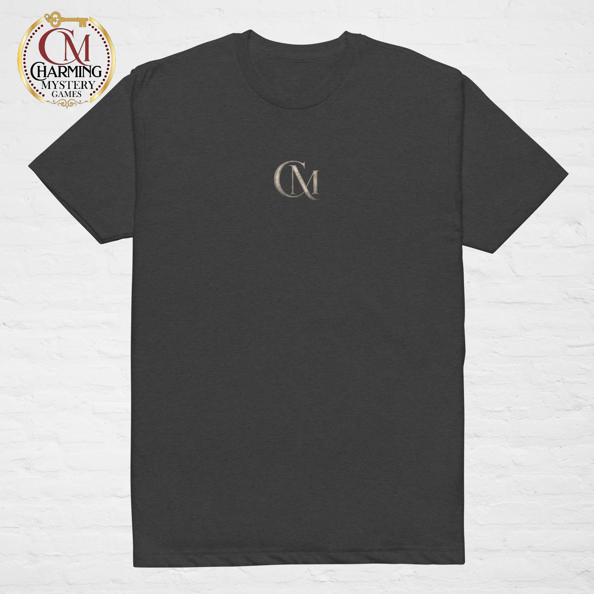 Product mockup of a gray tee shirt that has a CM logo on it for Charming Mystery Games. 